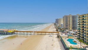 A beachside hotel with a pier extending into the ocean, a swimming pool, and multiple balconies. - Updated Ocean Front Condo Aquamarine Suite 201 (Daytona Beach Shores)