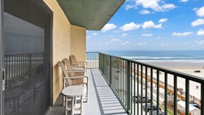 A balcony with a view of the beach, outdoor seating, and a covered area. - Tropical Palms Partial Ocean View Pool Hot Tub (Daytona Beach Shores)
