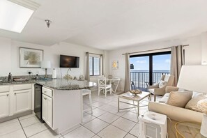 A modern living room with a kitchen, a dining area, and a balcony with a view. - Top Floor Oceanfront Condo w Pool Beach Access (Daytona Beach Shores)