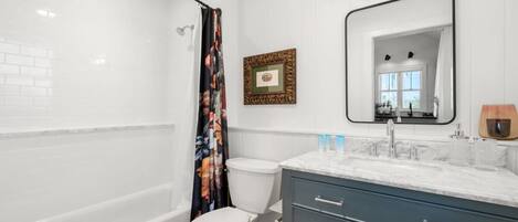 Un baño moderno con bañera, inodoro y tocador con espejo.