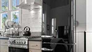 A modern kitchen with stainless steel appliances, including a refrigerator, oven, and kettle. - Romeo Julieta 2 Epic Studios Steps to 7th Ave (Tampa)
