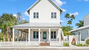 A two-story white house with a porch, a picket fence, and palm trees in the background. - Romeo Julieta 2 Epic Studios Steps to 7th Ave (Tampa)