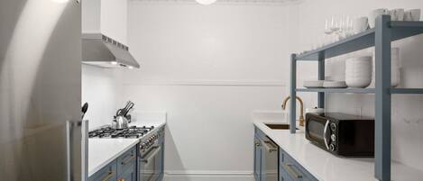 A compact kitchen with a gas stove, microwave, and a shelf with dishes.