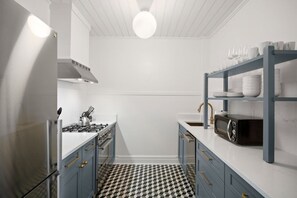 Une cuisine compacte équipée d’une cuisinière à gaz, d’un four à micro-ondes et d’une étagère pour la vaisselle.