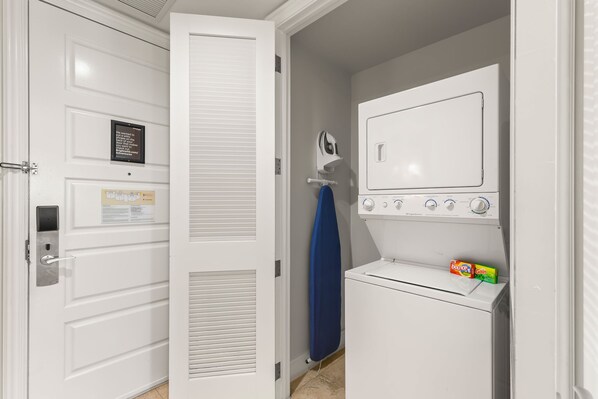A laundry room with a white dryer, a wall-mounted iron, and a door with a sign. - Resort View 1BR Suite (Key West)