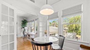 A bright room with a round table and chairs, large windows, and a white ceiling. - The Adaline 6 Gorgeous Hyde Park Apartment (Tampa)