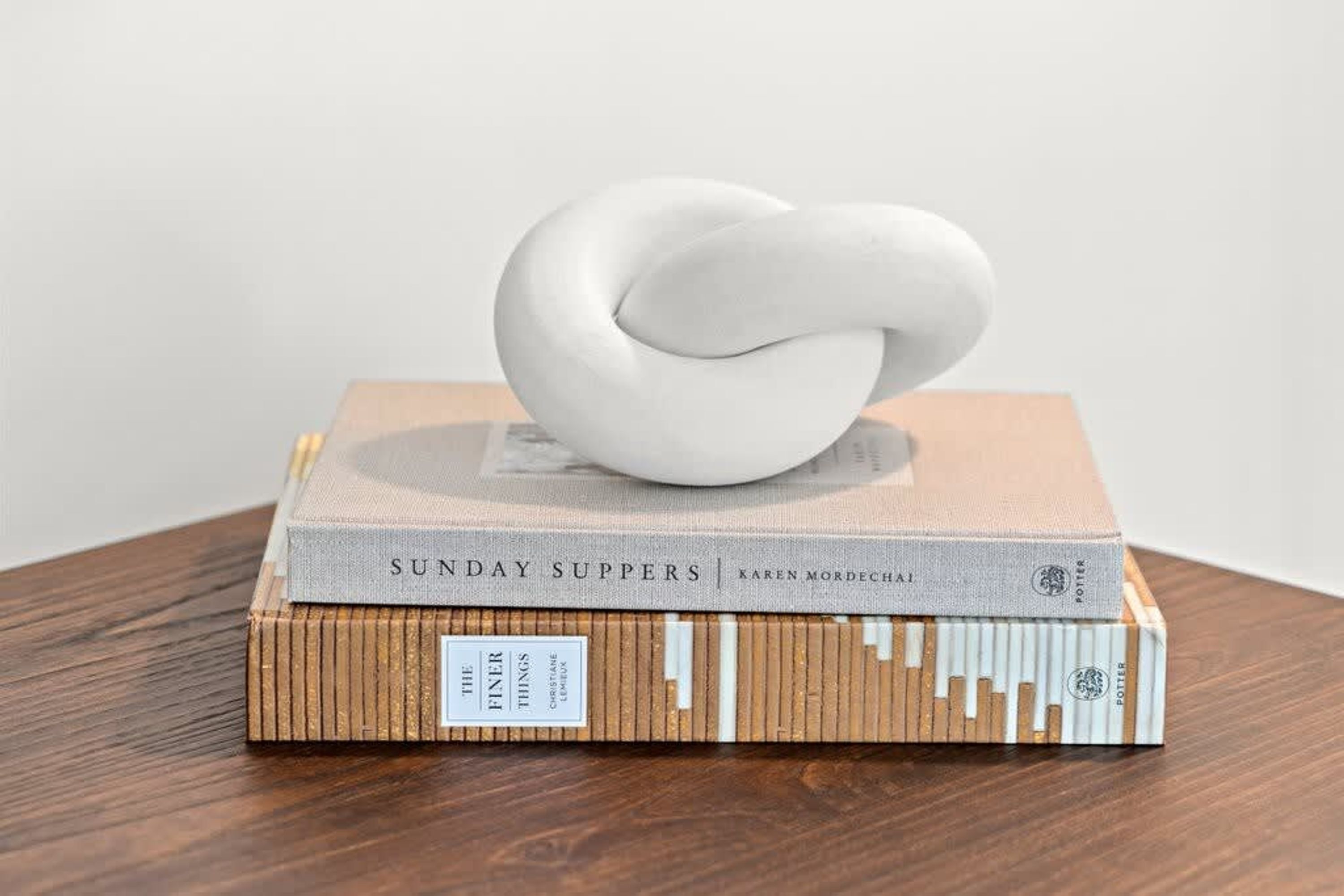 A stack of books with a white sculpture on top.