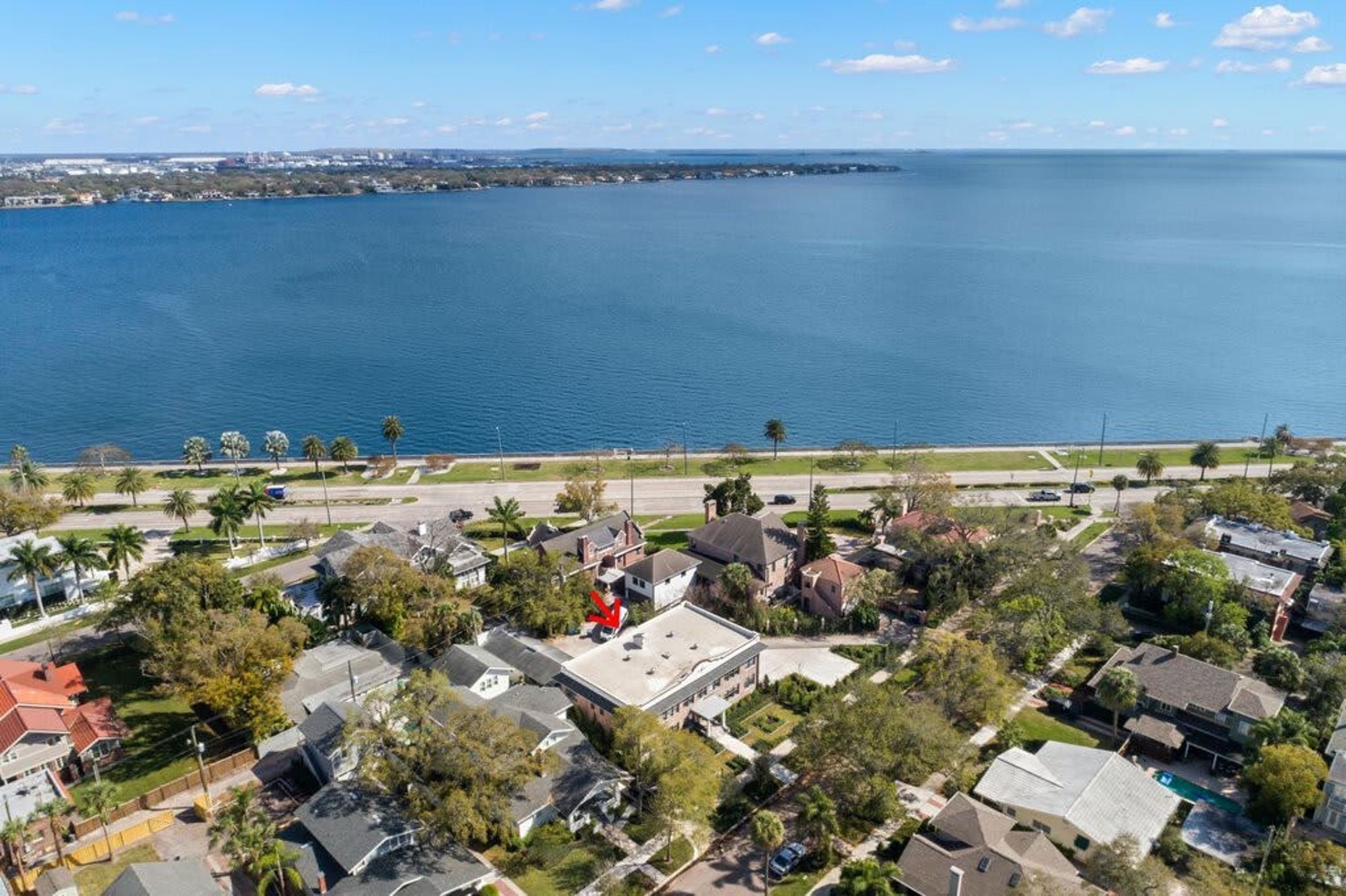 A residential area with houses, a road, and a large body of water in the background.