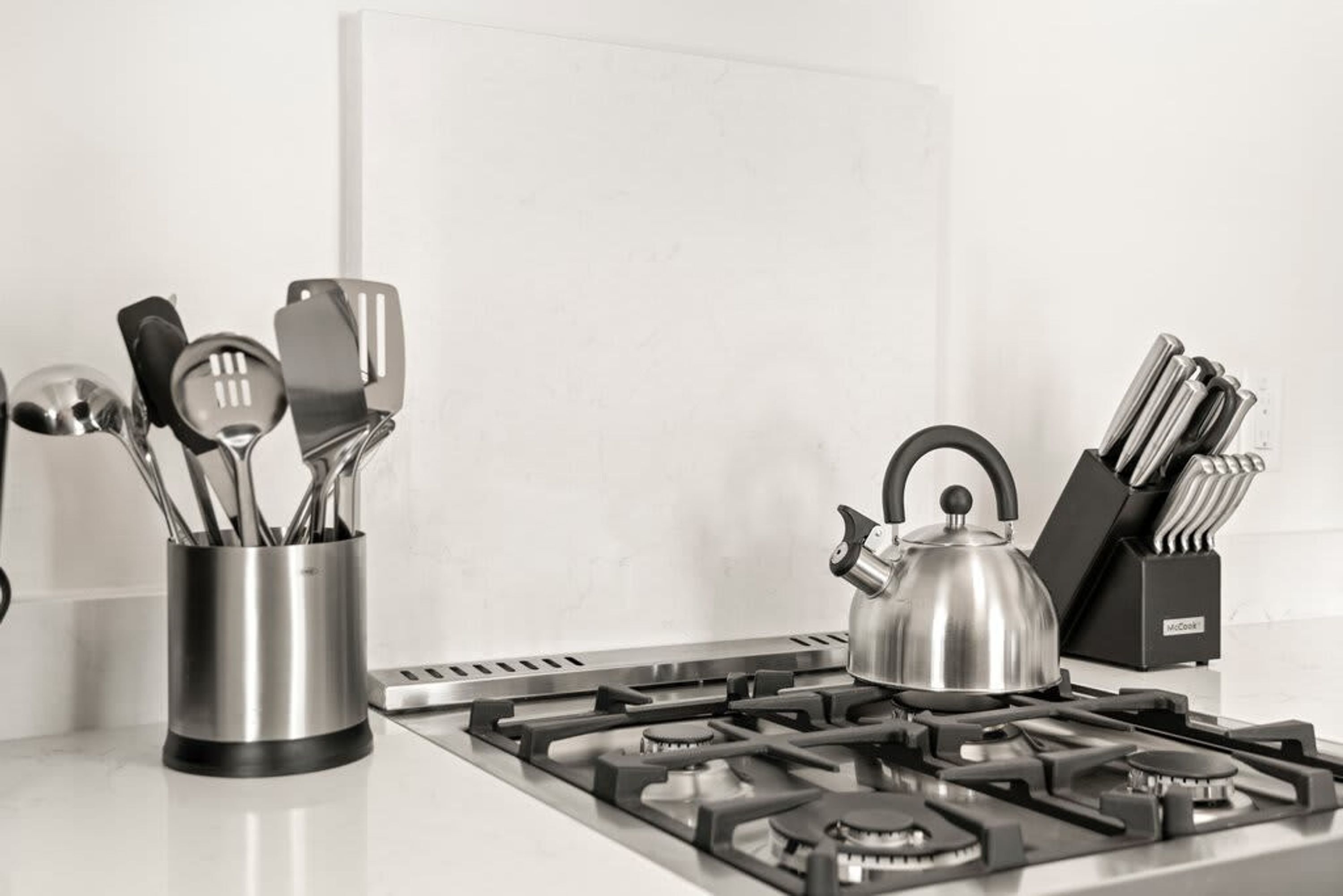 Une cuisine équipée d’une cuisinière à gaz, d’une bouilloire et d’un porte-ustensiles.
