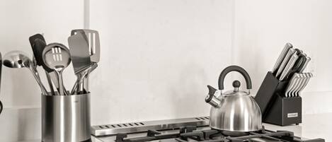 Une cuisine équipée d’une cuisinière à gaz, d’une bouilloire et d’un porte-ustensiles.