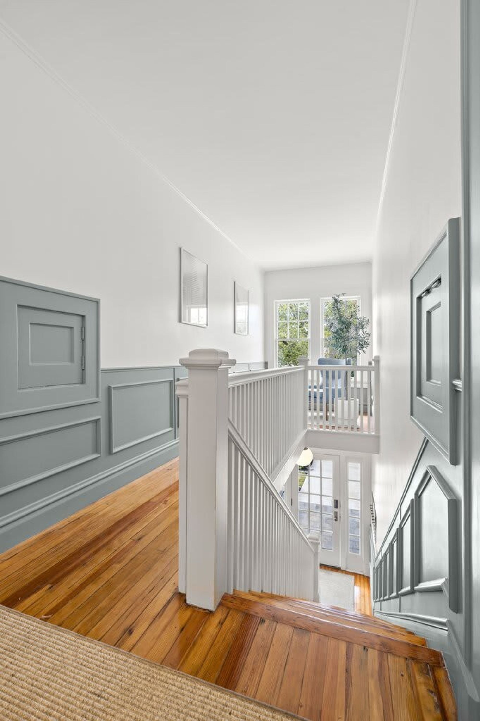 A staircase with white railings leading to a balcony with a view of greenery.