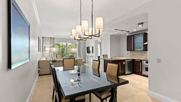A modern dining area with a glass table, chairs, and a chandelier.