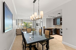 Ein moderner Essbereich mit einem Glastisch, Stühlen und einer Chandelier.