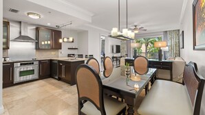 A modern kitchen with dark cabinetry, stainless steel appliances, and a dining area with a glass-top table and chairs. - Resort View 2BR Residence (Key West)