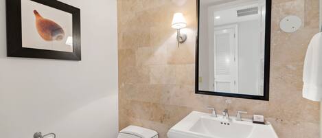 A bathroom with a toilet, sink, and a framed picture on the wall.