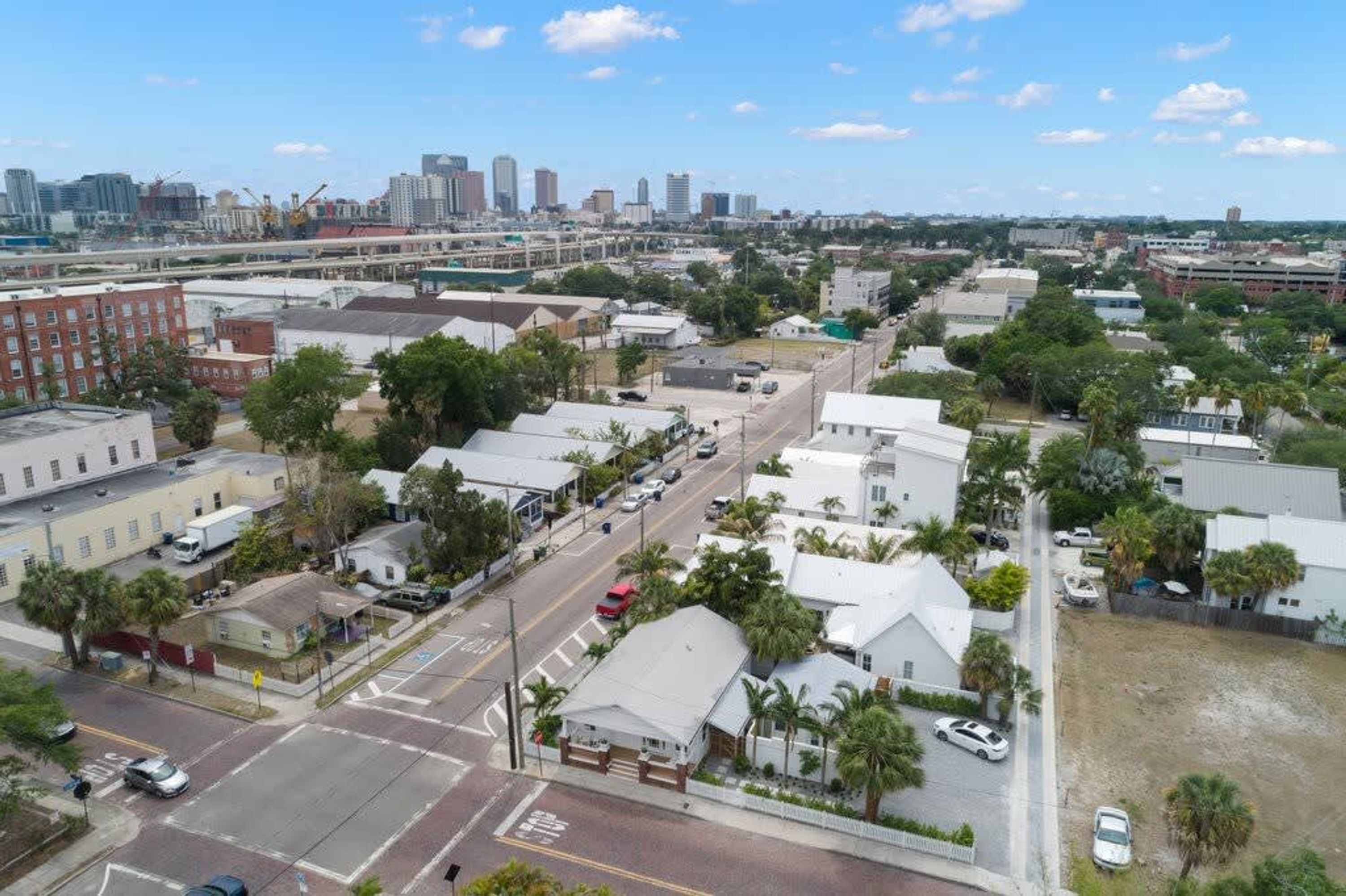 An aerial view of a cityscape with a mix of commercial and residential buildings, roads, and a distant skyline.