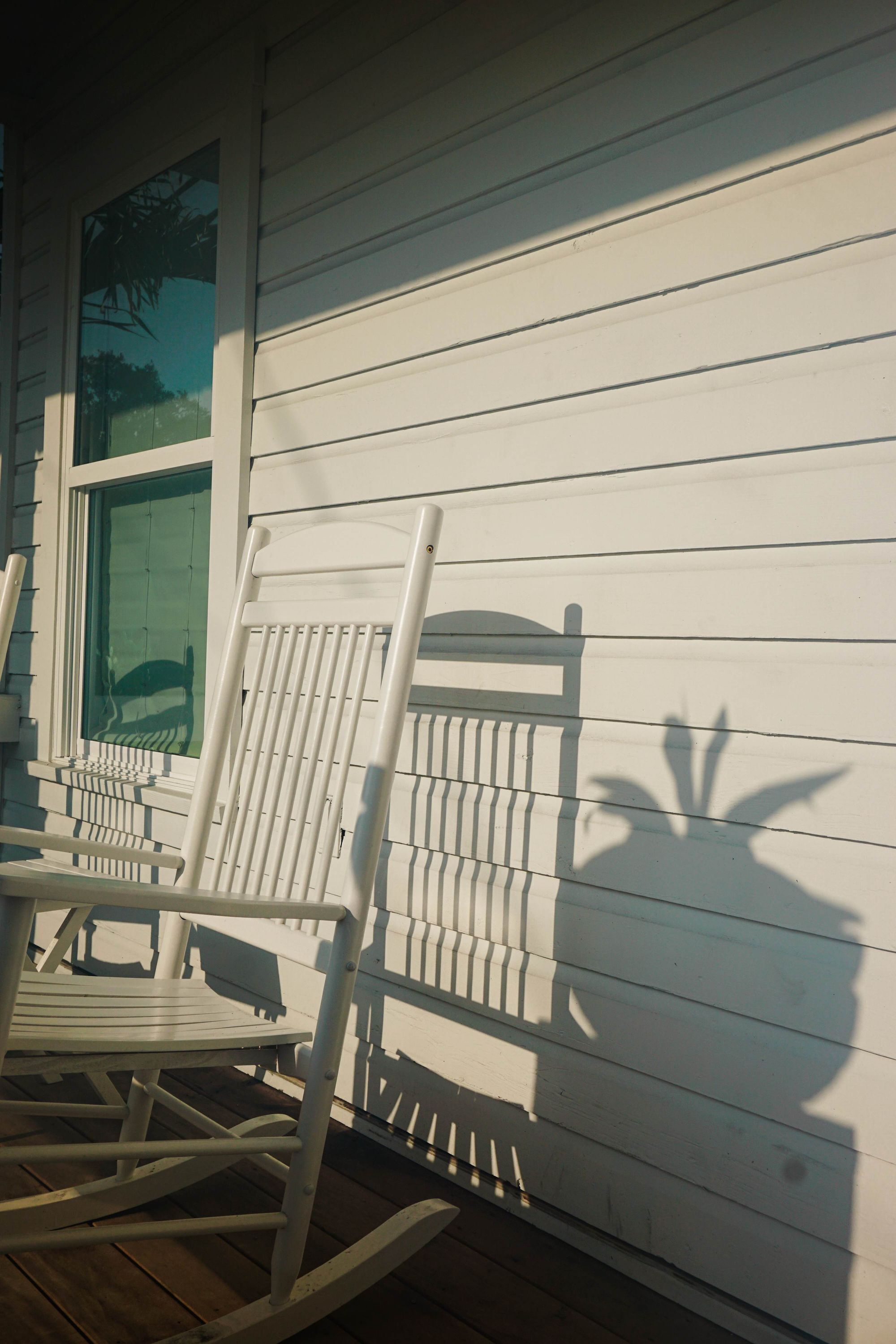 A wooden deck with a rocking chair and a table.