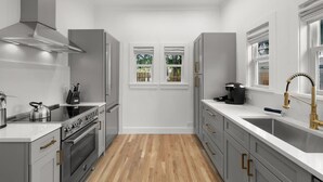 Een moderne keuken met witte kasten, een roestvrijstalen fornuis en een houten vloer.