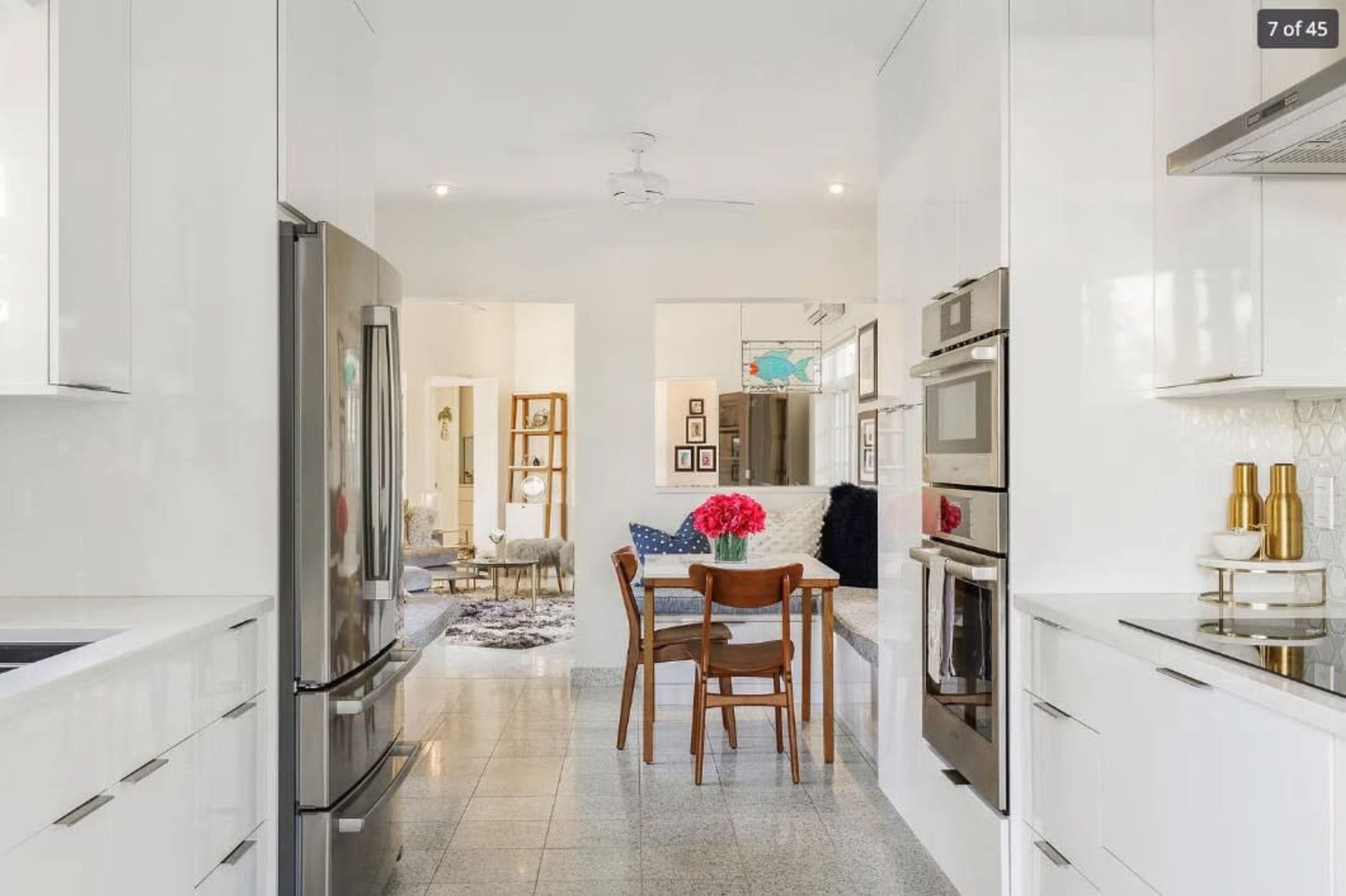A modern kitchen with white cabinetry, stainless steel appliances, and a dining area with a table and chairs.