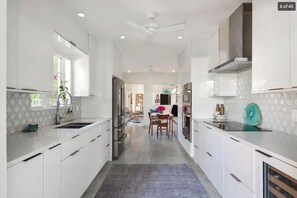 Une cuisine moderne avec des meubles blancs, un îlot central et un coin repas à l’arrière-plan.