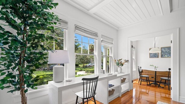 A bright, white room with wooden floors, a desk with a chair, and a large window overlooking a garden. - NEW The Adaline 4 Updated Hyde Park Apt (Tampa)