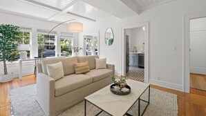A modern living room with a beige sofa, a coffee table, and a large window with a view of greenery. - NEW The Adaline 4 Updated Hyde Park Apt (Tampa)