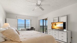 A bedroom with a bed, a TV, a desk, and a balcony with a view. - Reflections 504 Oceanfront Pool Beach View (Indian Rocks Beach)