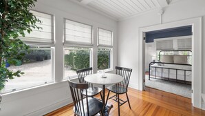 A room with a round table and four chairs, large windows, a bed with a headboard, and a view of the outdoors. - The Adaline 3 Hyde Park Apt Steps to Bayshore (Tampa)