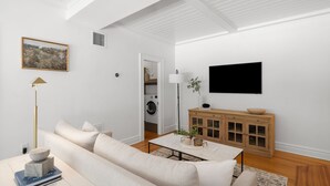 A modern living room with a sofa, coffee table, and a television mounted on the wall. - The Adaline 3 Hyde Park Apt Steps to Bayshore (Tampa)
