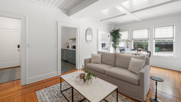 A spacious living room with a beige sofa, a coffee table, and a view of the outdoor patio. - The Adaline 3 Hyde Park Apt Steps to Bayshore (Tampa)