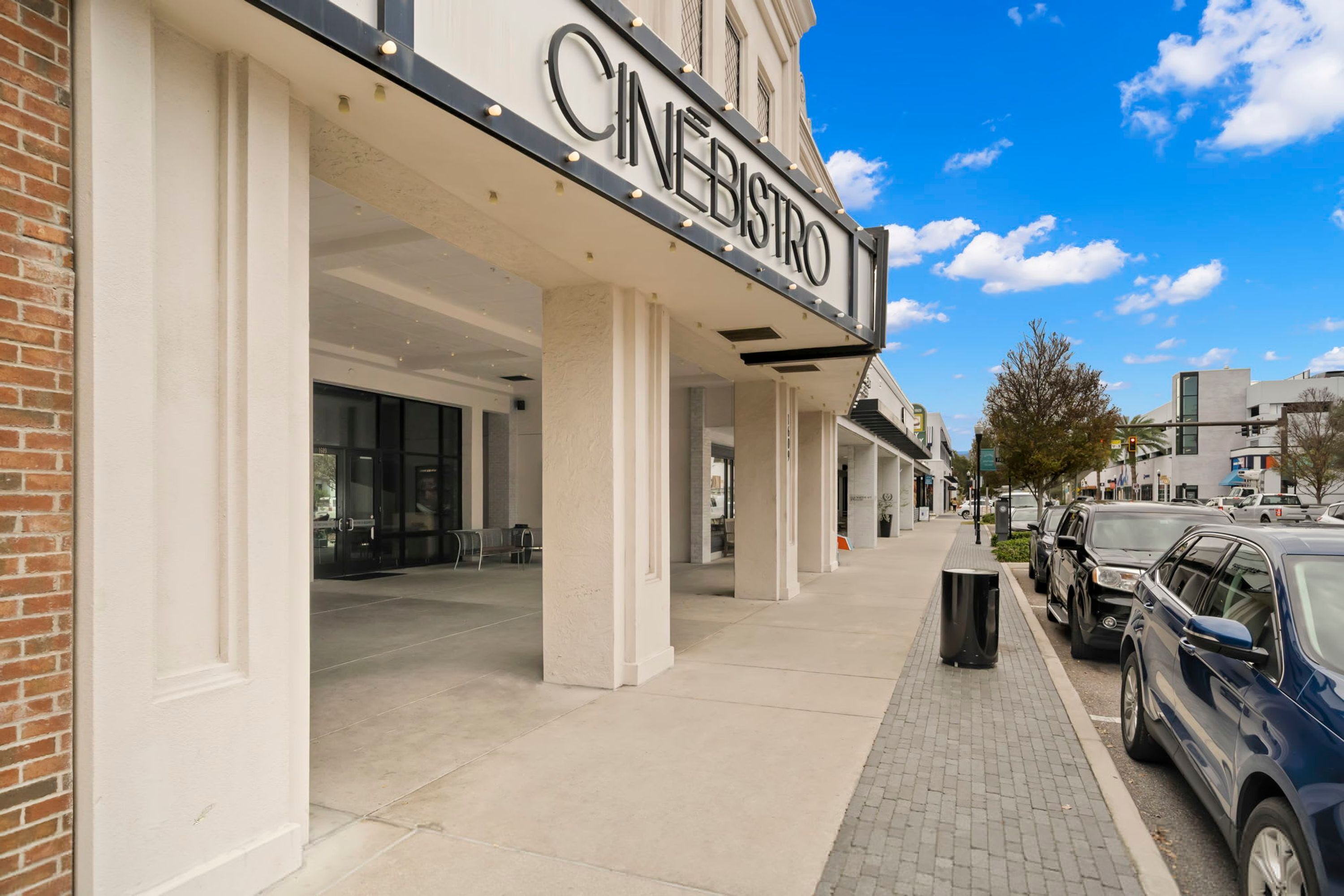 A cinema with a marquee sign, outdoor seating area, and a paved sidewalk.