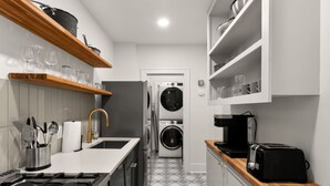Pieni, käytännöllinen keittiö, jossa on kaasuliesi, pesukone ja leivänpaahdin.