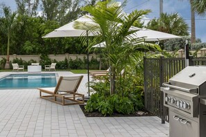 A backyard with a swimming pool, a barbecue grill, and outdoor seating. - Ebberly House by Brightwild Amazing Pool (Key West)