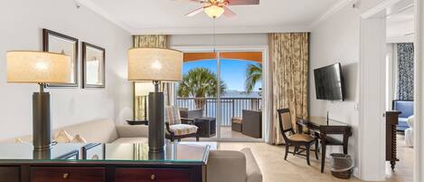 Una habitación de hotel con balcón, zona de comedor y televisor.
