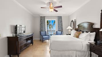 A hotel room with a large bed, a dresser, a television, a ceiling fan, and a window with curtains.