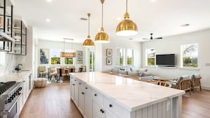 Una cocina amplia con una isla grande, piso de madera e iluminación colgante.