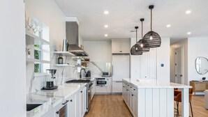 A modern kitchen with white cabinetry, a central island, and pendant lighting.