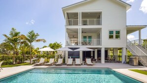 A two-story house with a pool, outdoor seating, and a covered patio.