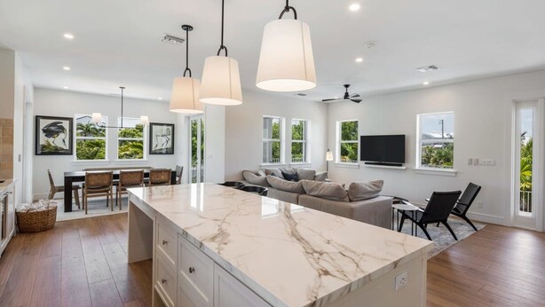 A spacious kitchen with a marble island, pendant lighting, and a dining area with chairs and a table.