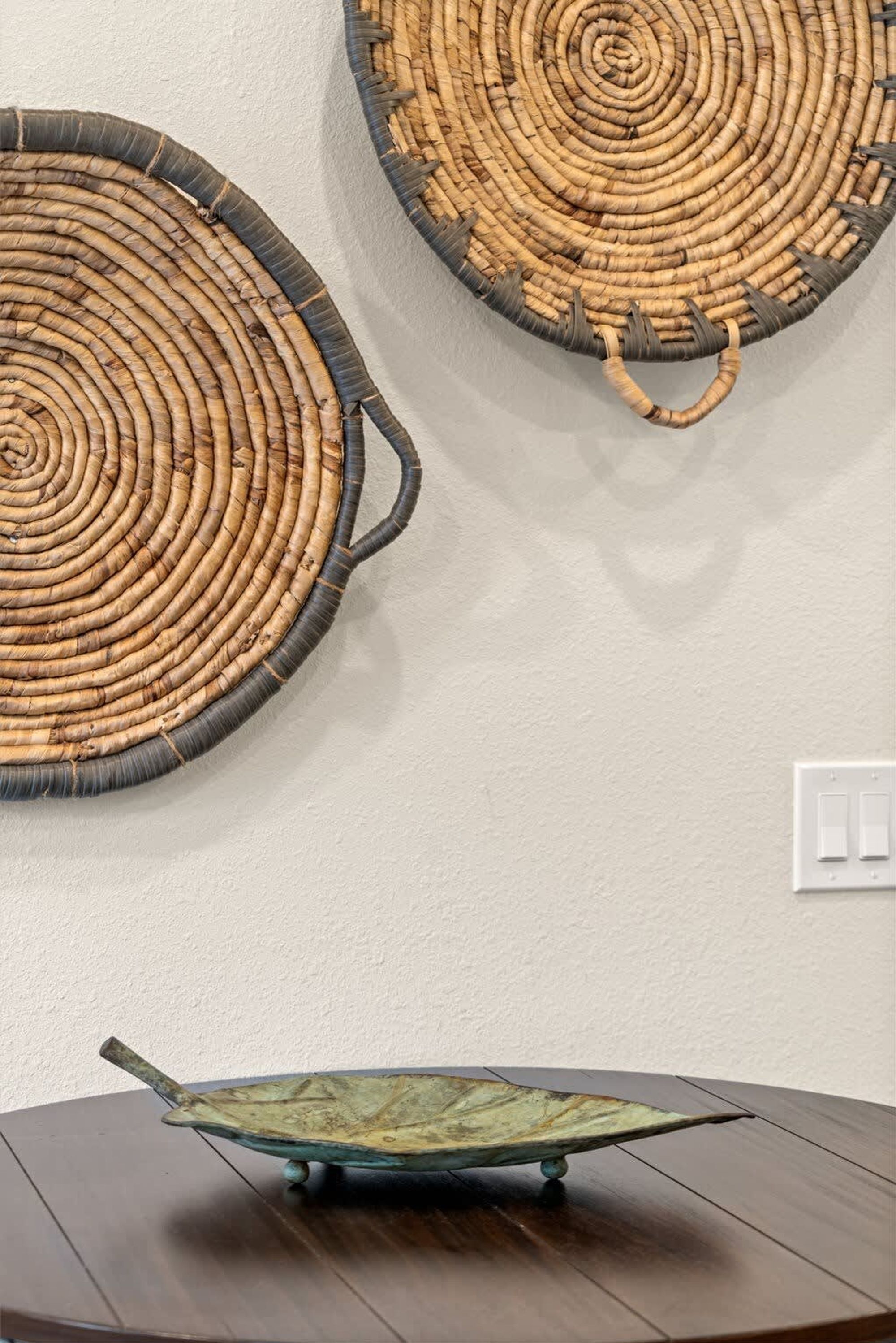 A round woven wall hanging and a small, round, green metal table.