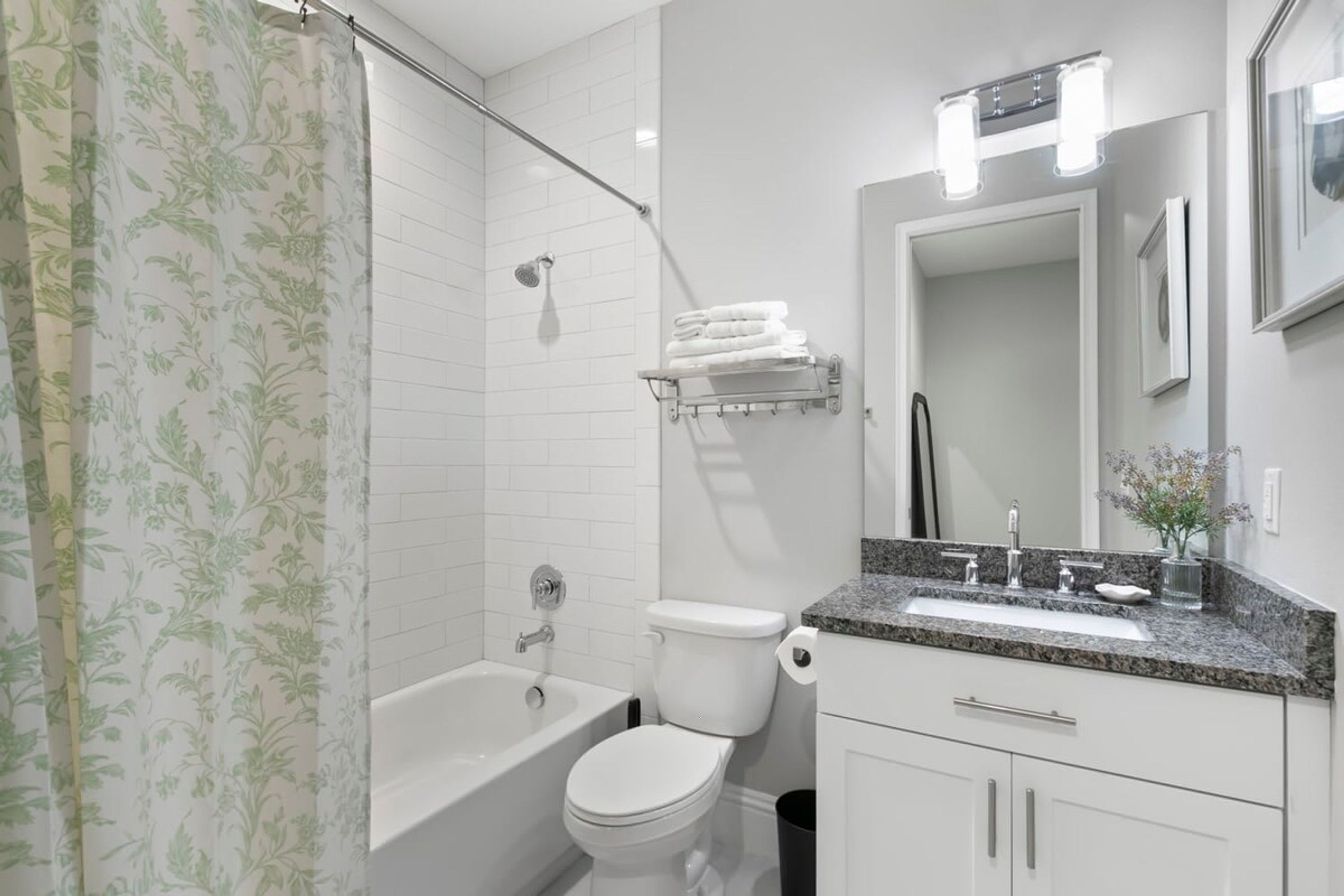 A modern bathroom with a bathtub, toilet, and vanity with a sink and mirror.