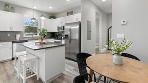 A modern kitchen with white cabinets, stainless steel appliances, and a central island with stools.