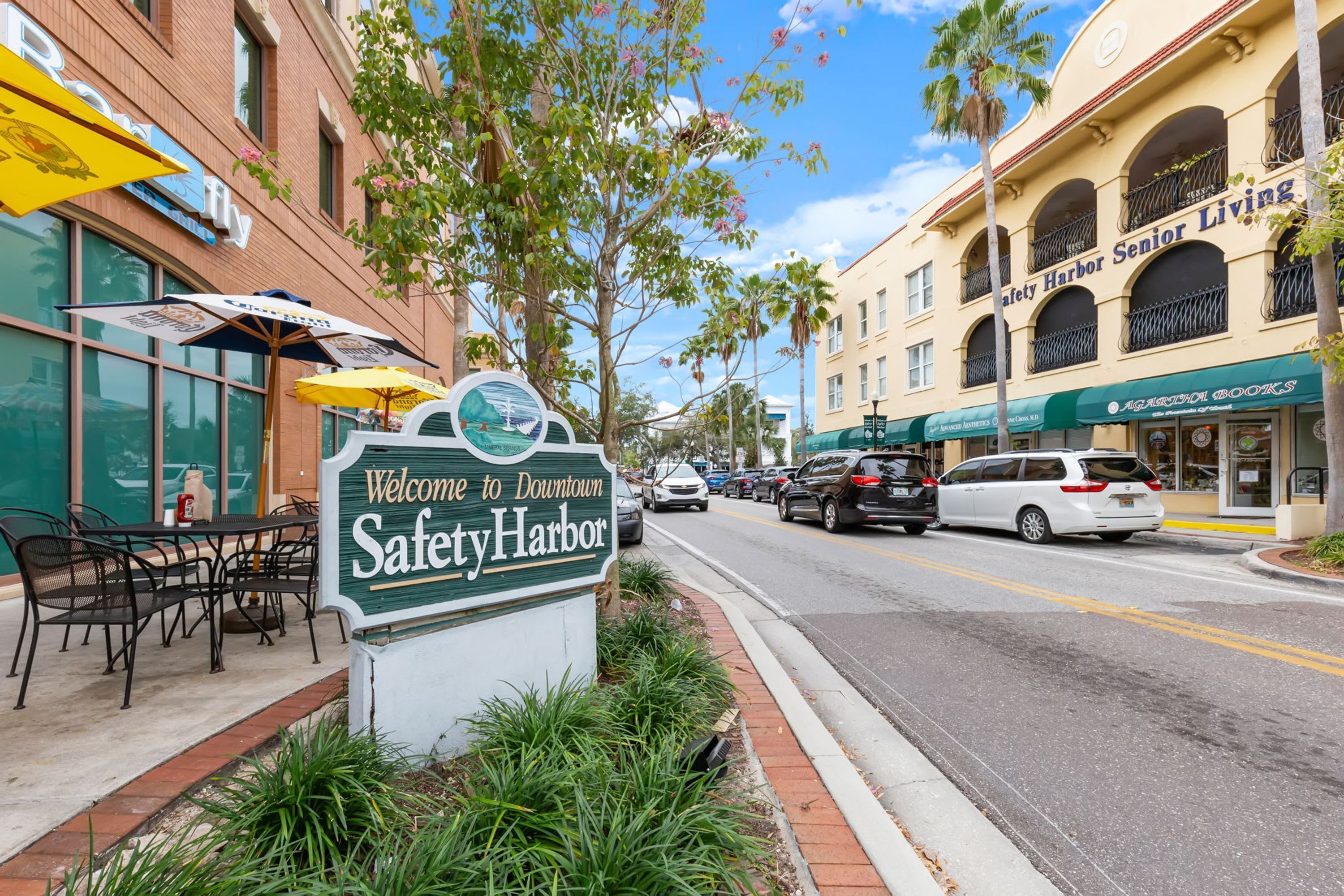 A street sign for Downtown Safety Harbor with a restaurant and a senior living facility nearby.