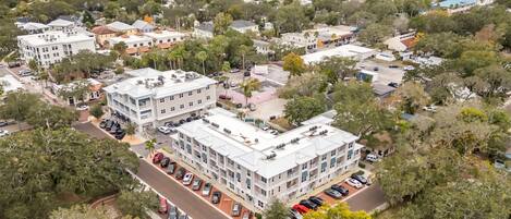 An aerial view of a residential area with multiple buildings, a parking lot, and a body of water in the background.