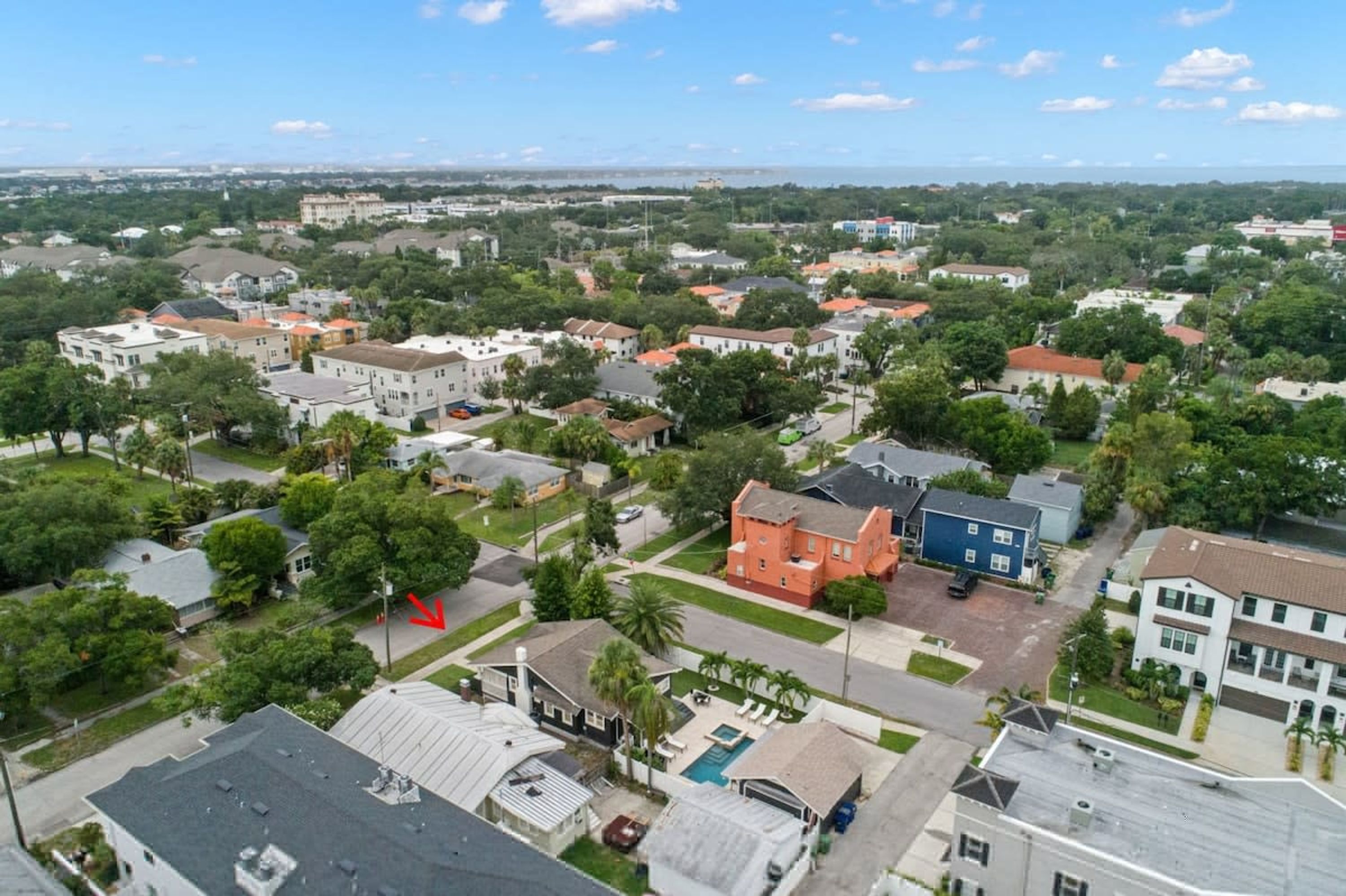 An aerial view of a residential area with houses, a swimming pool, and a red building.