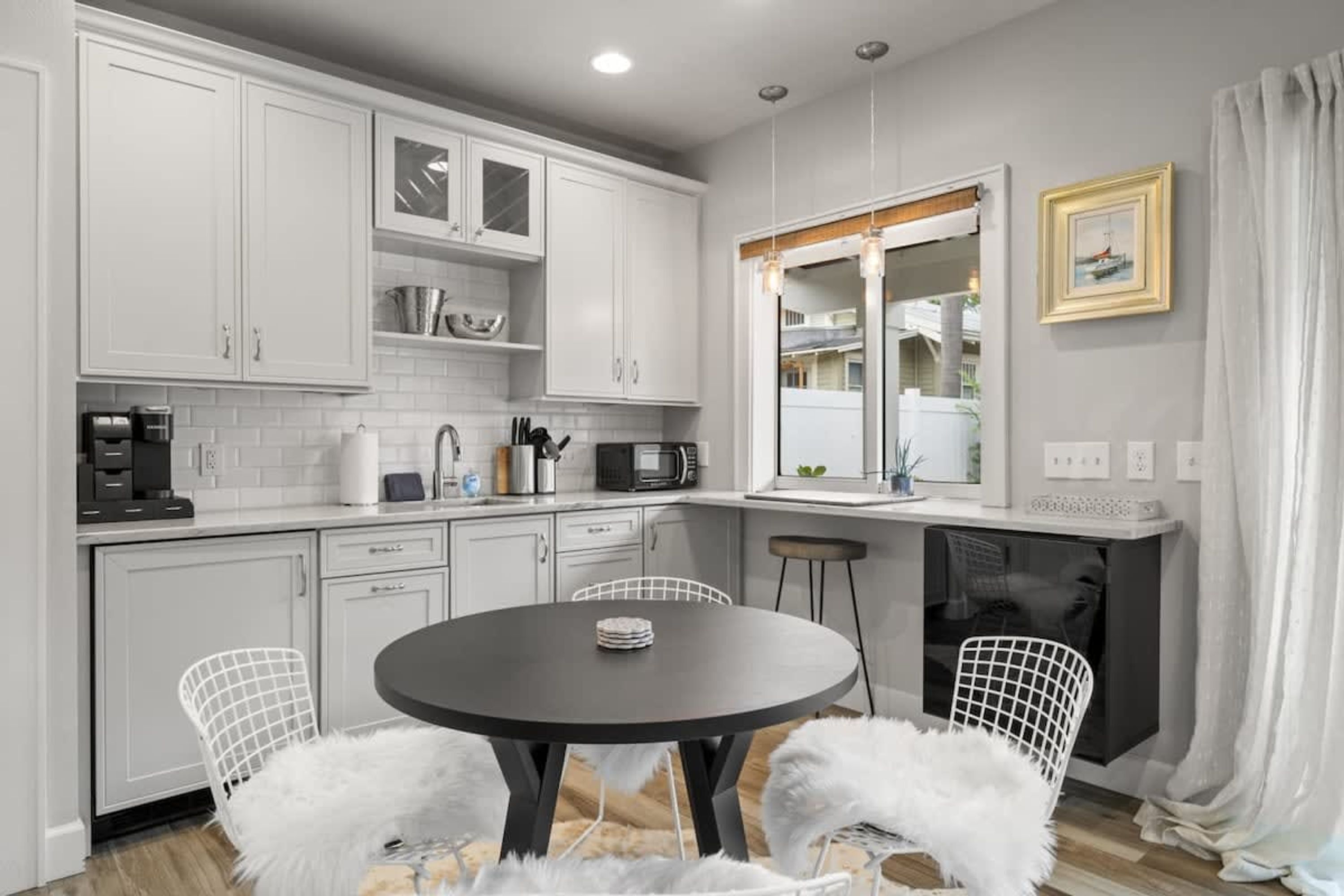 A modern kitchen with white cabinetry, a round dining table, and two white chairs.