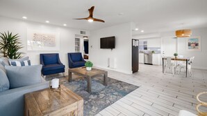 A modern living room with a sofa, two armchairs, a coffee table, and a dining area with a table and chairs. - Stunning 2BR Suite, Just Steps to the Beach (Clearwater Beach)