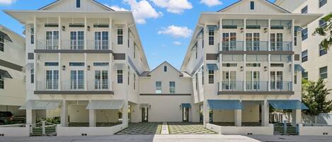 A symmetrical building with a central entrance, multiple balconies, and a flat roof.