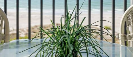 Enjoy breathtaking ocean views from this balcony with a glass table and comfortable wicker chairs.