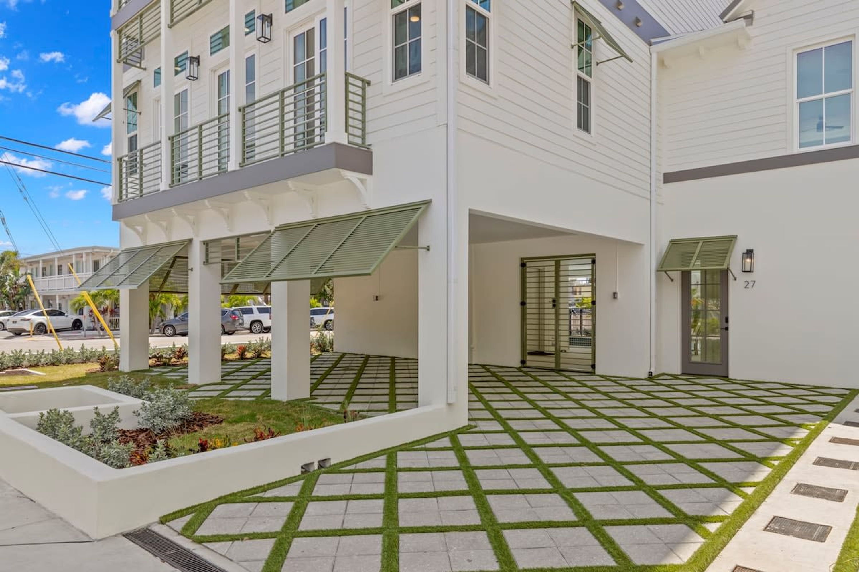 A modern building with a covered outdoor area, a tiled patio, and a small garden.
